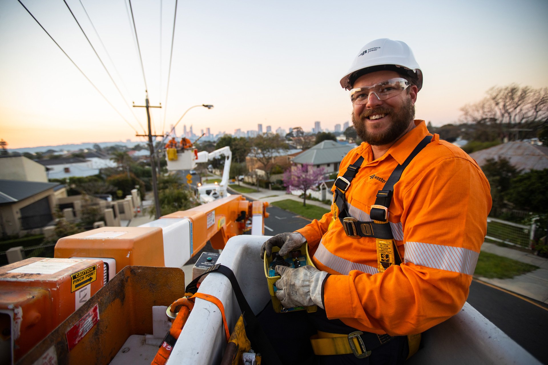A Western Power crew member in an elevated work platform carrying out work on an overhead power line