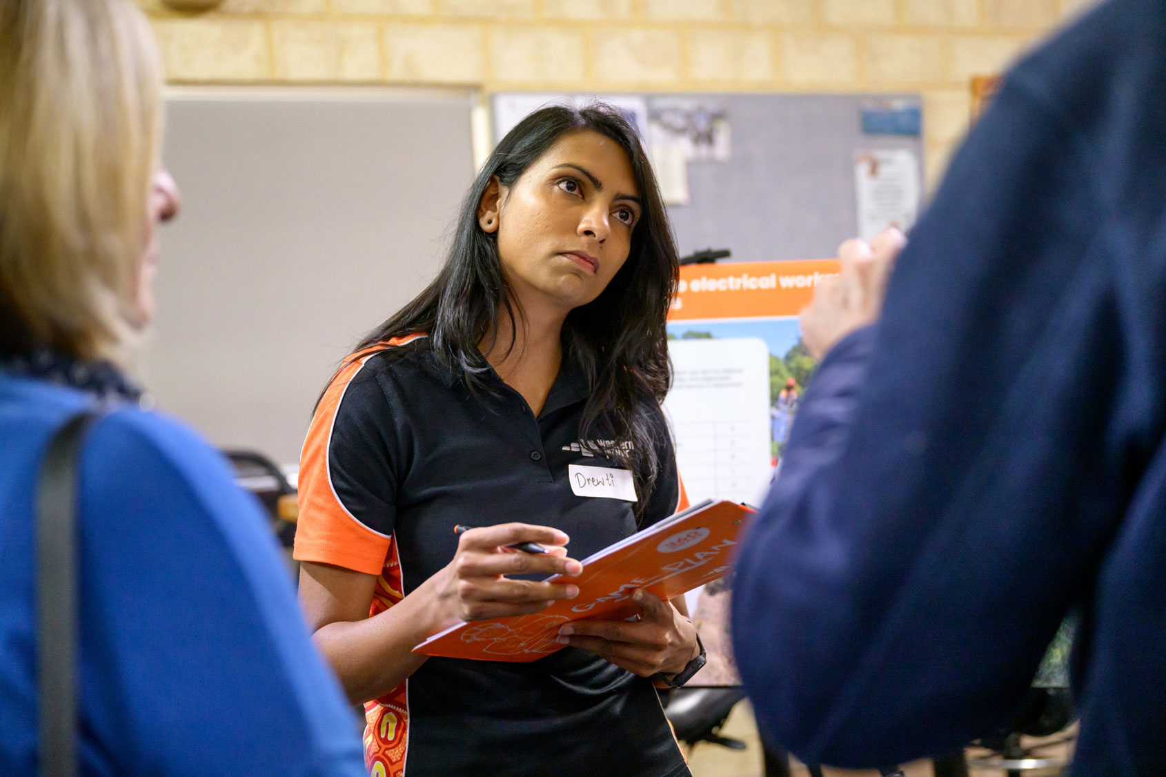 Western Power employee holding a clipboard while listening members of the community