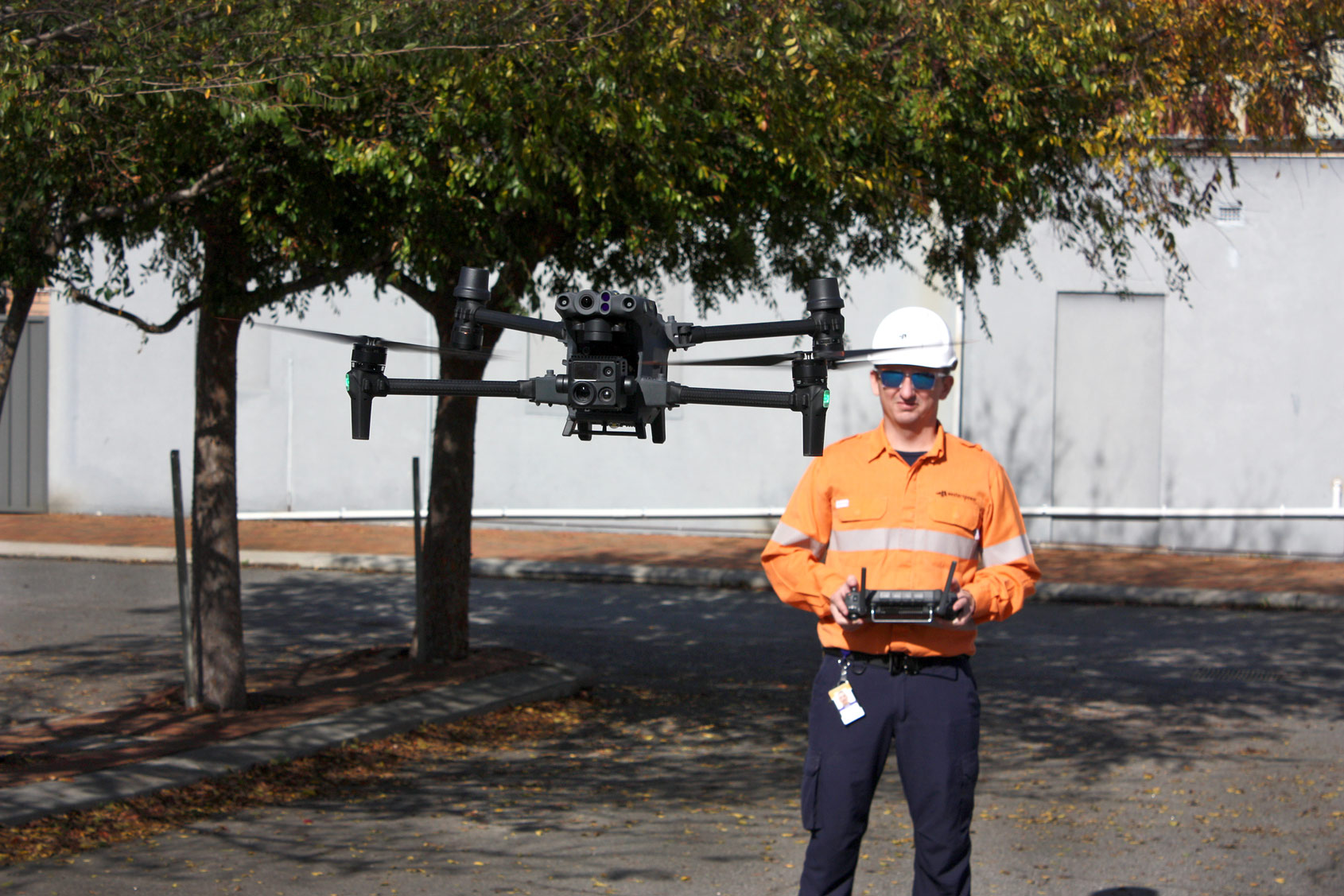Western Power field crew holding remote while drone is hovering in front of them.